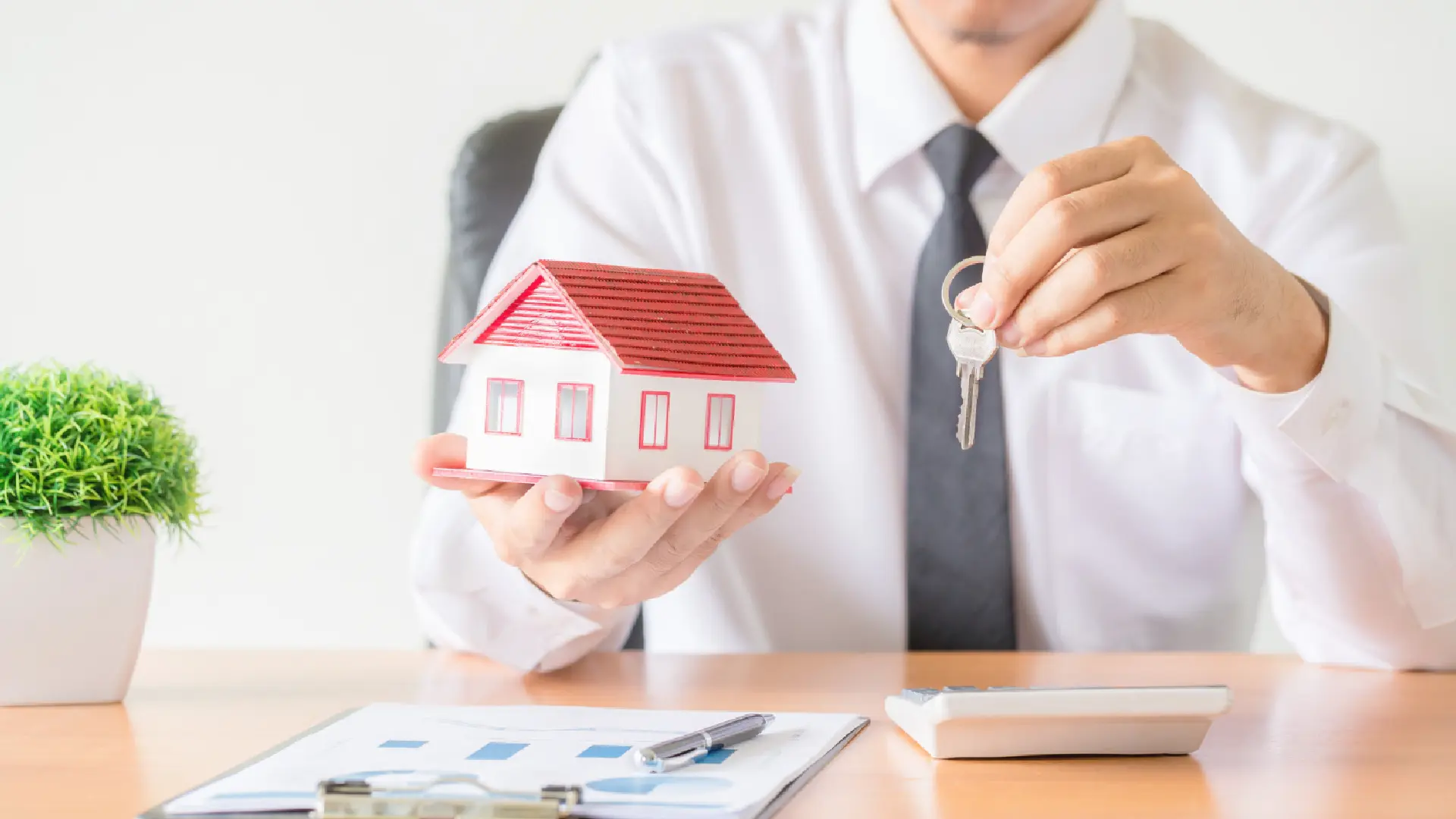 Real estate agent holding a house model and keys, representing how AI cold calling helps property agents in Singapore close more sales