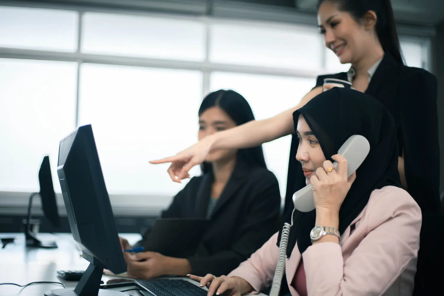 Team of telemarketers on calls in a Singapore office, illustrating the cost comparison between human telemarketers and AI cold calling